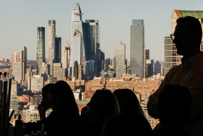 Two business professionals in a conference room having a serious discussion, with a city and water view in the background.