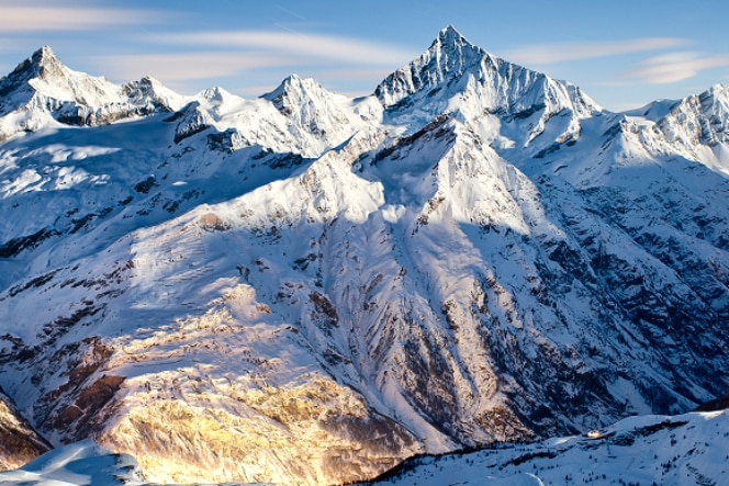 A woman in a black outfit looks up at a curved, modern architectural structure with white walls and soft lighting. The perspective emphasises the building's sweeping design and open space.