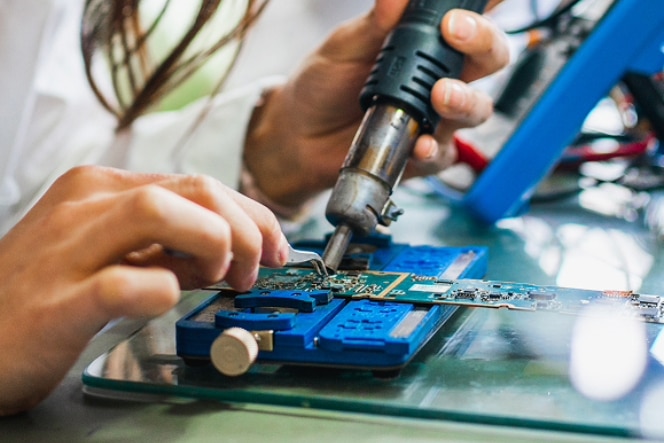 A man stands by a window in a dimly lit office, looking out at a large American flag waving outside, its reflection casting across the room.